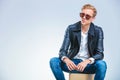 Skinny man wearing sun glasses and leather jacket while sitting Royalty Free Stock Photo