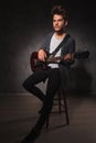 Skinny rocker playing guitar while sitting and looking away Royalty Free Stock Photo