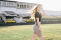 A skinny, slim student standing in sportswear at Stadium in Background of Tribunes. Evening Time