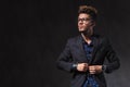 Skinny young man wearing glasses is fixing his jacket in studio