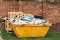 Skip bin full of household waste rubbish on the front yard. House clean up and renovation concept