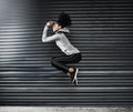 Skip over the challenges you face towards your goals. a sporty young woman jumping against a grey background.
