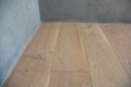 Skirting Board and Architrave. Close up on oak wood flooring, thin solid wooden skirting boards with gray plastered walls.