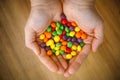 Skittles multicolored fruit candies in woman hands. Wooden background