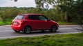 Skoda Fabia Mk2 second generation 5J in motion on the country road. Red car driving fast on the rural way, rear side view Royalty Free Stock Photo