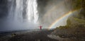 Skogafoss waterfall with an unidentified man under the waterfall and a rainbow, Skogar, Iceland Royalty Free Stock Photo