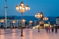 Night scene with people walking at the city square illuminated with decorative street lights in Skopje.