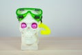Skull sculpture with pink eyes in a snorkeling green mask and yellow tube