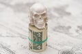 A skull standing on a bundle of money, twisted into a bundle