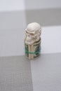 A skull standing on a bundle of money, twisted into a bundle