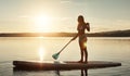 Sky above, earth below, peace within. an attractive young woman paddle boarding on a lake. Royalty Free Stock Photo