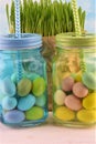 Sky-blue and green transparent glass jars with colored Easter eggs and green grass Royalty Free Stock Photo