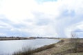 Sky, clouds. Meandering river. Green grass on the low banks of the river. In the distance, a forest, a village, rain clouds