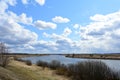 Sky, clouds. Meandering river. Trees, shrubs, grasses on the low banks of the river. Forest in the distance. Rural view Royalty Free Stock Photo