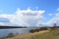 Sky, clouds. Trees, shrubs, grasses on the banks of the river. A village in the distance. Rural view Royalty Free Stock Photo