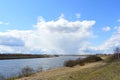 Sky, clouds. Trees, shrubs, grasses on the banks of the river. A village in the distance. Rural view Royalty Free Stock Photo