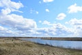 Sky, clouds. Wind. Meandering river. Grass on the low banks of the river, a bench. Forest in the distance. Rural view Royalty Free Stock Photo