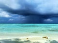 A sky with dark storm clouds. A rain over a calm sea. Maldives, a beach with the white sand near the turquoise ocean. Royalty Free Stock Photo