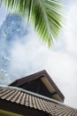 The sky is full of smoke. The roof of the building against the background of smoke, palm leaf. symbol of the beginning Royalty Free Stock Photo