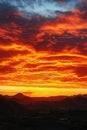 The sky is orange and the sun is setting. The clouds are low and the mountains are in the background Royalty Free Stock Photo