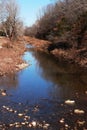 Sky Reflecting in Narrow Blue Creek lined with Stones and leaves in the Fall Winter Royalty Free Stock Photo