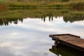 A dam, a jetty, reflected clouds and a meadow in a landscape