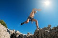 Sky runner with sweaty muscular body running in mountain and jumping over the cleft cliff during the morning jogging. Active Royalty Free Stock Photo