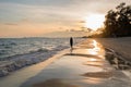 Sky and sea at sunset. Silhouette of young woman walking on ocean beach. Royalty Free Stock Photo