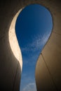 Sky shown through a curvy concrete structure .