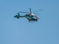 Flying in blue sky green white helicopter