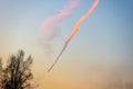 In the sky trace of an airplane flying towards the sun, tree silhouette Royalty Free Stock Photo