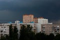 The sky is very dark blue over multi storey buildings before a thunderstorm