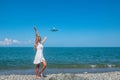 Skybound Connection: Girl in White Dress Meets a Plane Above the Blue Sea Royalty Free Stock Photo