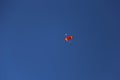 Skydiver against a clear blue sky with a colorful parachute