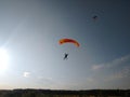 A skydiver with a bright orange sports parachute wing flies before landing Royalty Free Stock Photo