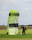 A skydiver gathering up his green chute