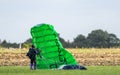 A skydiver gathering up his green chute