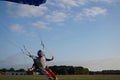 Skydiver under a dark blue little canopy of a parachute is landing on airfield, close-up