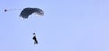 A skydiver with a white parachute canopy against a blue sky and white clouds, close-up. Royalty Free Stock Photo