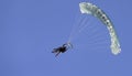 A skydiver with a white parachute canopy against a blue sky and white clouds, close-up Royalty Free Stock Photo