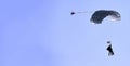 A skydiver with a white parachute canopy against a blue sky and white clouds, close-up Royalty Free Stock Photo