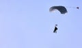 A skydiver with a white parachute canopy against a blue sky and white clouds, close-up. Royalty Free Stock Photo