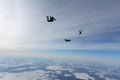 Formation skydiving in the winter sky above snowy fields.