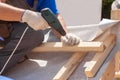 Skylight installation. Roofer builder worker use skrewdriver to fasten a wooden beam.