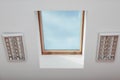 Skylight roof window and lamps on slanted ceiling in attic room, bottom view Royalty Free Stock Photo