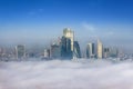 The skyline of the City of London peaking out of the fog