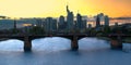 Skyline of a German city with skyscrapers shortly before the setting of the sun, with river and bridge in foreground Royalty Free Stock Photo