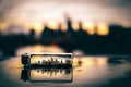 Skyline reflected in a small bottle lying in a puddle Sunset over the Main river in Frankfurt.