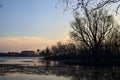 Skyline of a town seen from the distance over a lake at sunset framed by trees