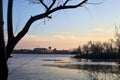 Skyline of a town seen from the distance over a lake at sunset framed by trees